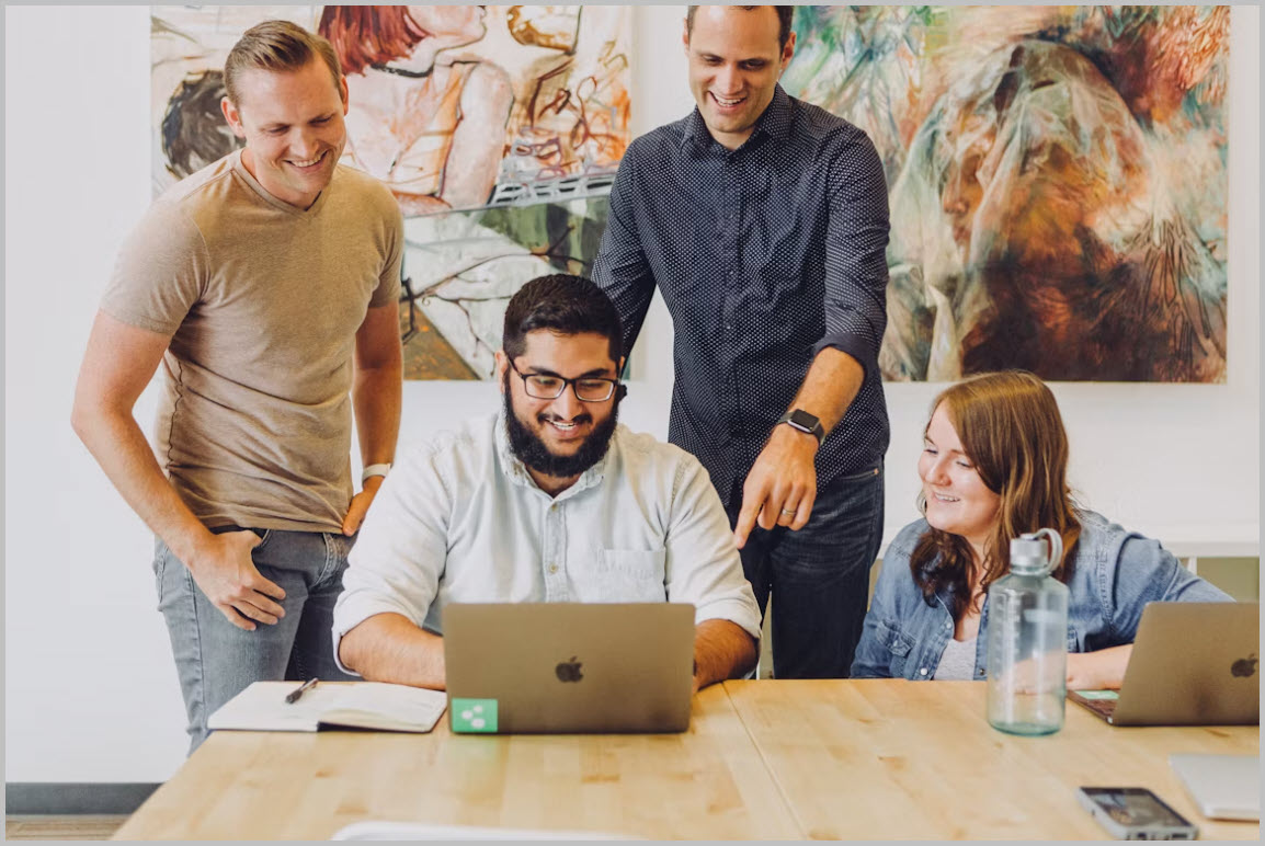 Team members collaborating around a laptop
